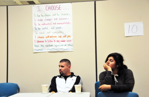 At the Silver Star Resource Center in Salinas, mentors Jose Coronado and Ariana Lopes listen to Leo Jimenez underneath a sign stating the group's pledge.